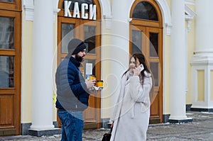 Love story of couple walking in city. Young business man in a blue jacket with a beard. And a cute woman in long coat