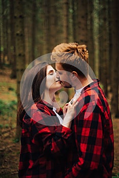 Love story photo  a couple in red shirts hugging and kissing on a hike. Beautiful couple in love in red shirts passionately