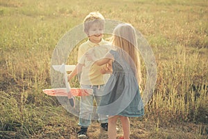Love story. Two happy children boy and girl playing with toy airplane over meadow having fun and smiling. Happy kids -