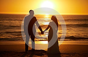 Love, summer and couple at a beach at sunset, silhouette holding hands and bonding with ocean views in nature. Romance