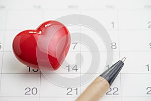 Love symbol or romance of valentine`s day concept with shiny red lovely heart shape with pen on 14 Feb white clean calendar
