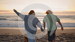 Love teenagers running sandy beach evening back view. Carefree couple enjoying