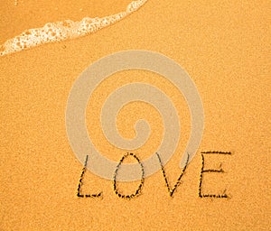 Love - text written by hand in sand on a beach
