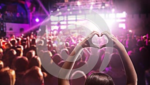 Love to music. Female heart shaped hands and crowd or audience at live music concert