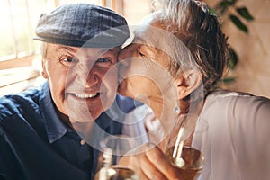 Love, toast and old couple kiss with champagne in celebration of a happy marriage anniversary together at home. Smile