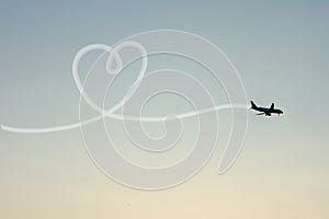 Love Travel Concept with Airplane Flying in the Sky Leaving Behind a Handmade Love Shaped Smoke Trail.
