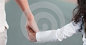 Love, trust and a girl holding hands with her parent while walking together outdoor on the road closeup. Family