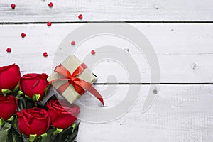 Love or Valentine concept with copy space for text. Red beautiful roses, heart and gift box on white wood background