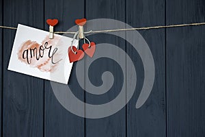 Love Valentine`s card `Amore` natural cord and red pins hanging on rustic Driftwood texture background, Copy Sp