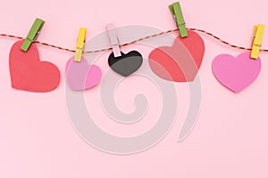 Love for Valentine's day - Red hearts hung together on the rope on pink background