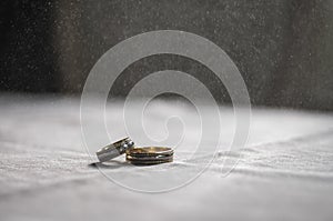 Love, Valentine`s day and wedding concept. Two wedding rings with man and woman hands blurred in the background. Selective focus