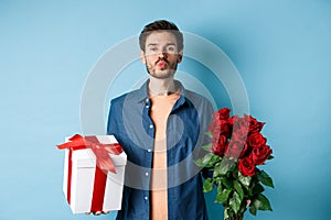 Love and Valentines day concept. Romantic boyfriend pucker lips for kiss, bring bouquet of red roses and gifts on date