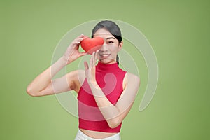 Love and valentines day woman holding heart smiling cute and adorable isolated on green background