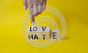 Love vs Hate symbol. Businessman Hand points at wooden cubes with words Hate and Love. Beautiful yellow background. Valentines day