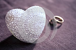 Love, wedding and Valentine`s day concept. Beautiful golden wedding rings and glass heart selective focus. useful as greeting card