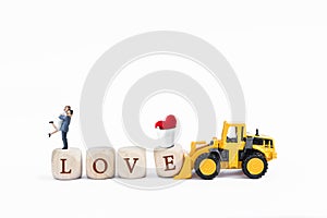 Love on wooden cubes with miniature couple and red heart with yellow truck isolate on white background