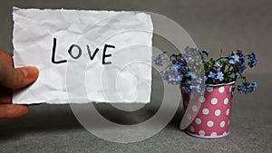 Love - word with blue flowers on gray background