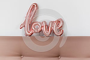 Love word from pink inflatable balloon on white background. The concept of romance, Valentine's Day. Love rose gold foil