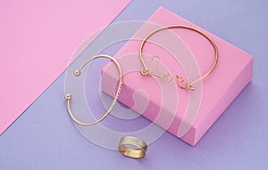 Love word shape bracelet and modern design bracelet and ring on pink and purple background with copy space