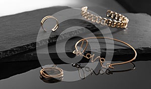 Love word shape and chain shape bracelets and rings on dark stone plates background