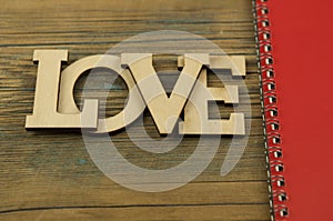 Love word, small hearts on dark wood background. Top view of Valentine`s Day