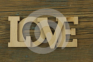 Love word, small hearts on dark wood background. Top view of Valentine`s Day