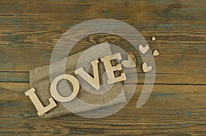 Love word, small hearts on dark wood background. Top view of Valentine`s Day