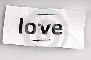 Love word written on torn and stapled paper