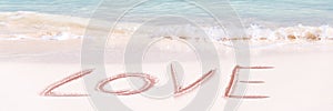 Love written on the white sand of an idyllic beach panoramic Valentines day banner