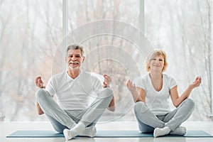 We love yoga training!Senior couple doing yoga in the class and looking at camera and smiling