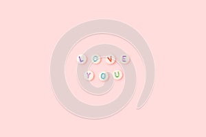 Love you. Quote made of white round beads with colorful letters.