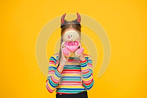 Love you. Small child cover face with teddy bear toy. Little girl in red devil horns hold valentines toy. Plaything. Toy
