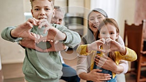 Love your family. Happy grandparents with grandchildren making heart sign with hands and smiling at camera while sitting