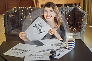 Love yourself. Calligrapher Young Woman writes phrase on white paper. Inscribing ornamental decorated letters