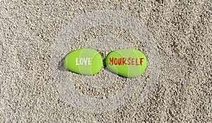 Love yourself symbol. Concept words Love yourself on beautiful green stone. Beautiful sand beach background. Psychology love