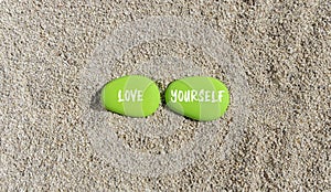 Love yourself symbol. Concept words Love yourself on beautiful green stone. Beautiful sand beach background. Psychology love