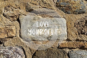 Love yourself symbol. Concept words Love yourself on beautiful grey stone. Beautiful brown stone wall background. Psychology love