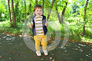 Lovely 2 years toddler boy in yellow trousers outdoors