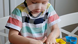 Lovely 4 years boy with playdough at home. Hands close up