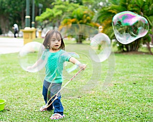 Lovely active little asian girl playing with soap bubble outdoor in the park