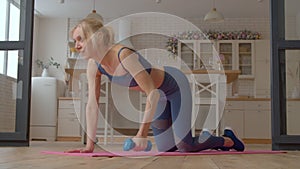 Lovely active sporty fit senior woman performing renegade row exercise at home