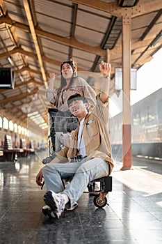 Lovely Asian couple are excited for their summer vacation, commuting by a train at a railway station