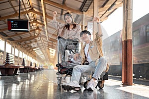 Lovely Asian couple are excited for their summer vacation, commuting by a train at a railway station