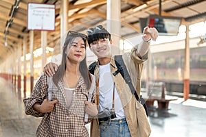 A lovely Asian couple of travelers are traveling by train together, waiting for their train