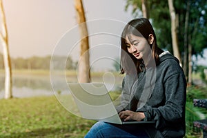 A lovely Asian girl is bright in the tourist area. There is a laptop computer in the hand on the road amid the fog. The back is a