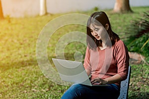 A lovely Asian girl is bright in the tourist area. There is a laptop computer in the hand on the road amid the fog. The back is a