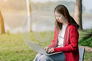 A lovely Asian girl is bright in the tourist area. There is a laptop computer in the hand on the road amid the fog. The back is a