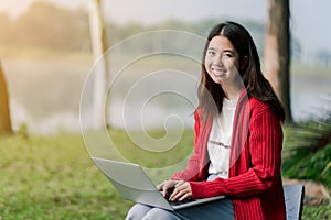 A lovely Asian girl is bright in the tourist area. There is a laptop computer in the hand on the road amid the fog. The back is a