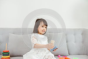 Lovely Asian girl playing toy at sofa at home