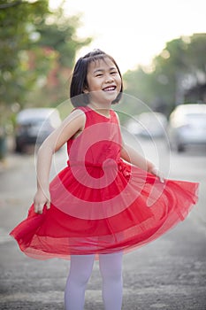 Lovely asian girl wearing red skirt dress moving with happiness face outdoor